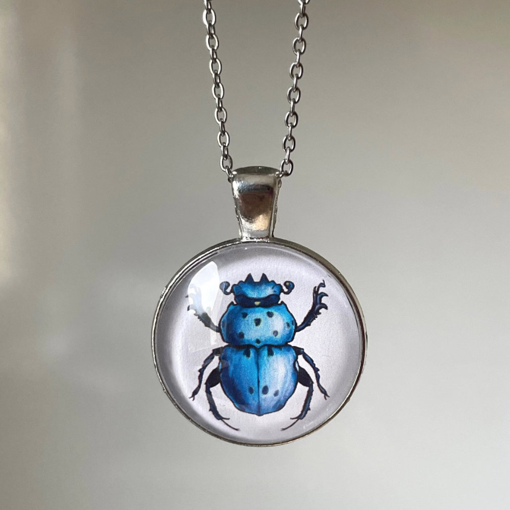Handmade cabochon necklace with original art of a blue scarab beetle, crafted by artist Boriana Giormova